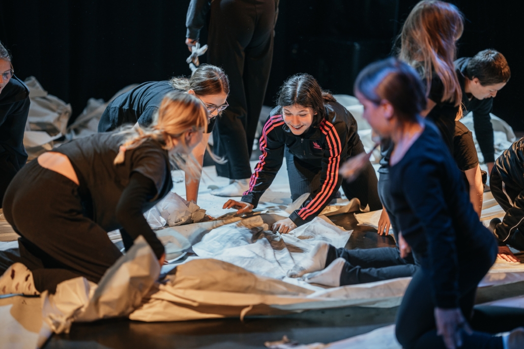 Mädchen sitzen auf dem Boden über ein Plakat gebeugt